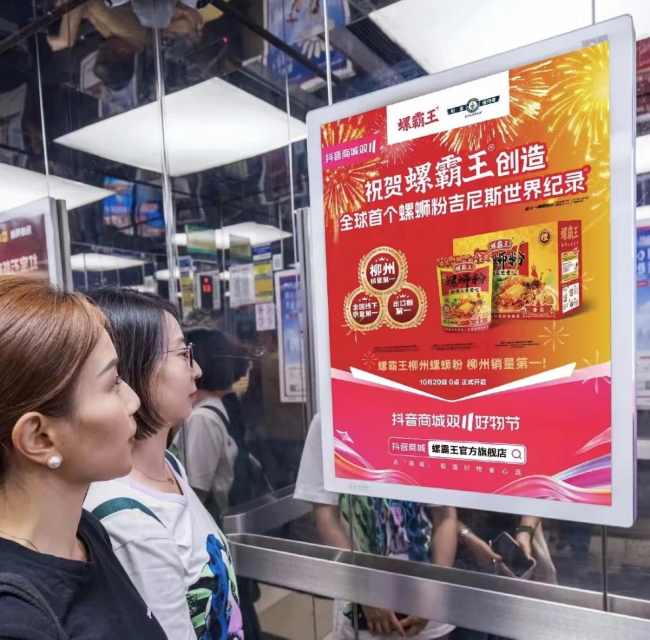 电梯框架广告大红色宣传画面乘客认真观看中