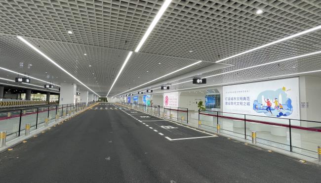 深圳机场网约车迎客区2条车道，旁边是玻璃幕墙内的候车区