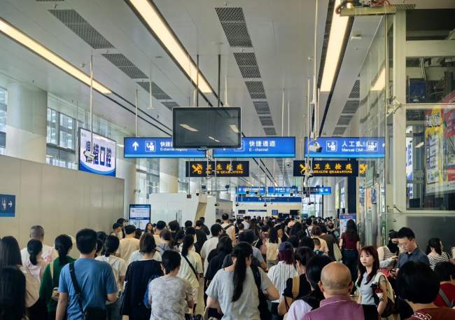 深圳福田口岸三层出境闸机前客流密集场景实拍图，鼎植口腔广告也出现在福田口岸通道区域