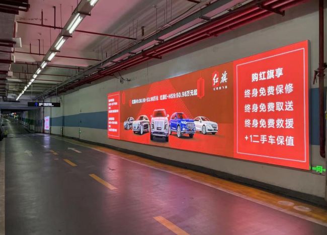 福州东百中心地库负三层A馆通道场景实拍图，图中墙面灯箱广告画面为红旗汽车