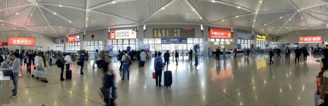 图为永康南高铁站候车大厅全景拍摄图，检票口两侧上方墙面是智能门安全门以及保温杯广告