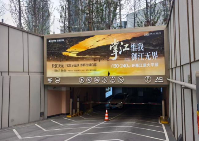 图为武昌滨江天街停车场出入口上方楣头灯箱广告，展示着长江天元地产广告信息